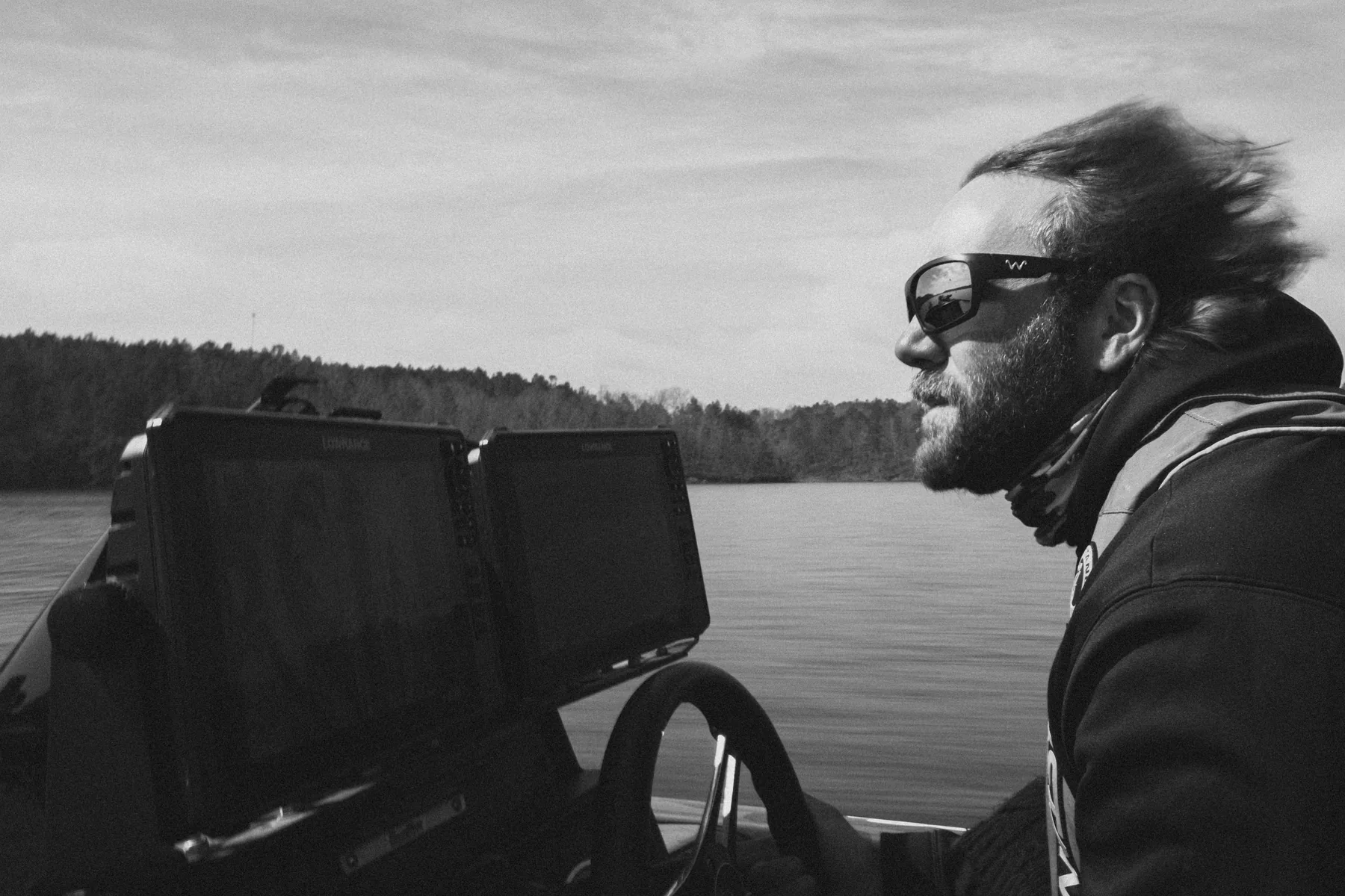 Black and white candid portrait of an angler at the helm of a boat
