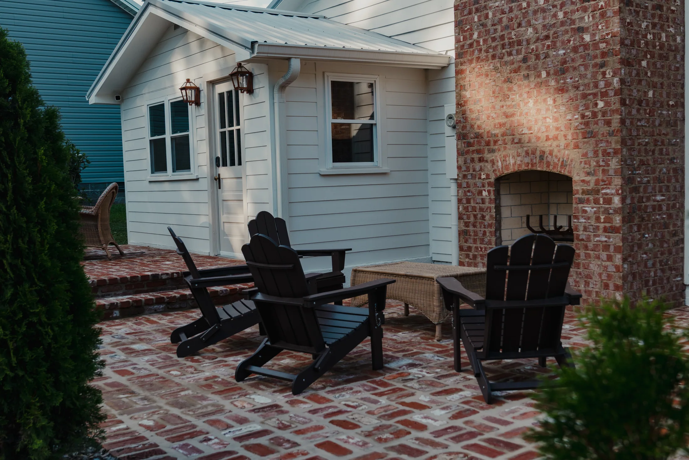 Brick patio and outdoor fireplace at a white residential property
