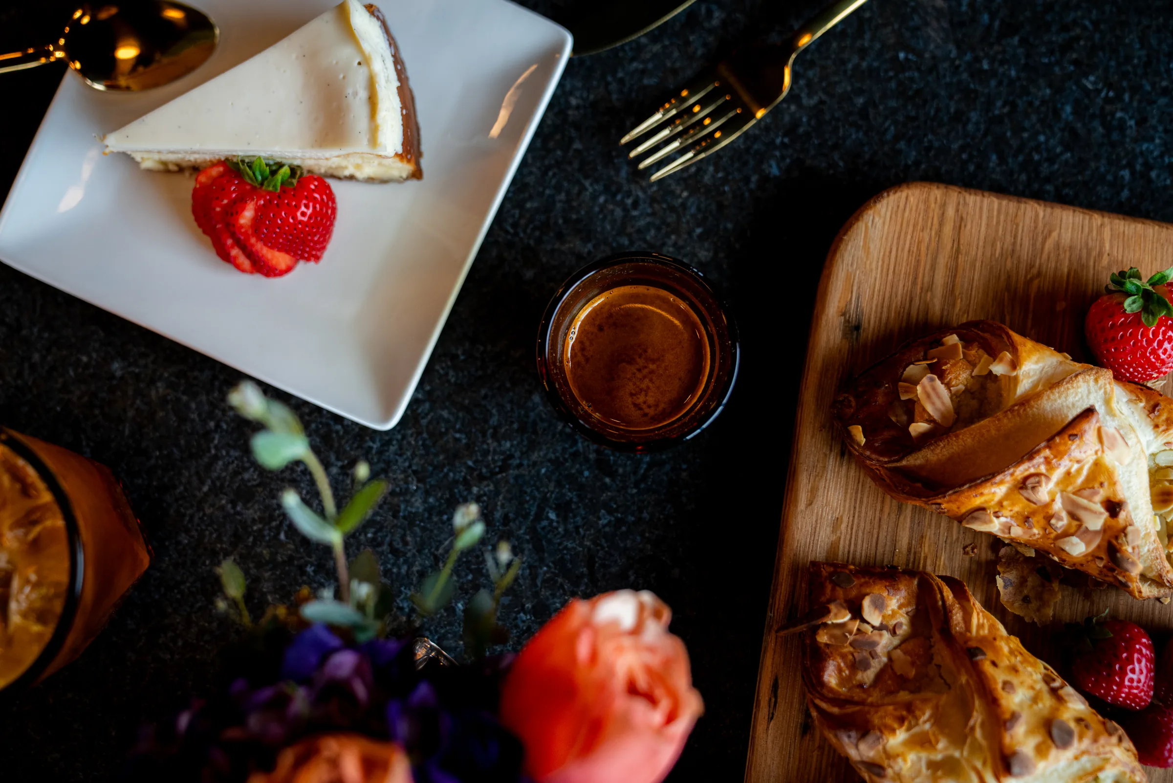 Cheesecake, pastries and strawberries arranged on a dark table