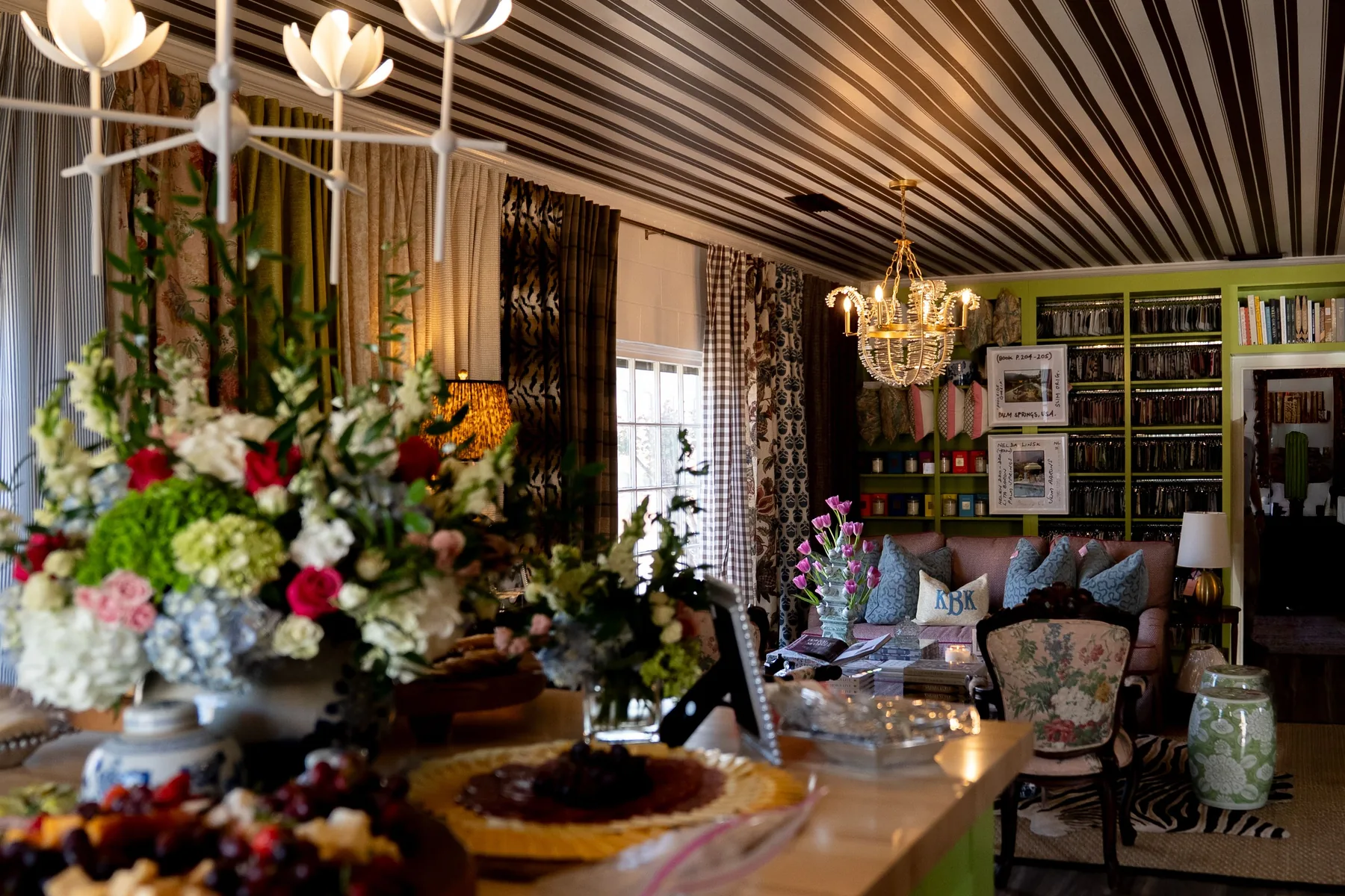 Patterned ceiling, colorful upholstery and floral arrangements in a designed living room