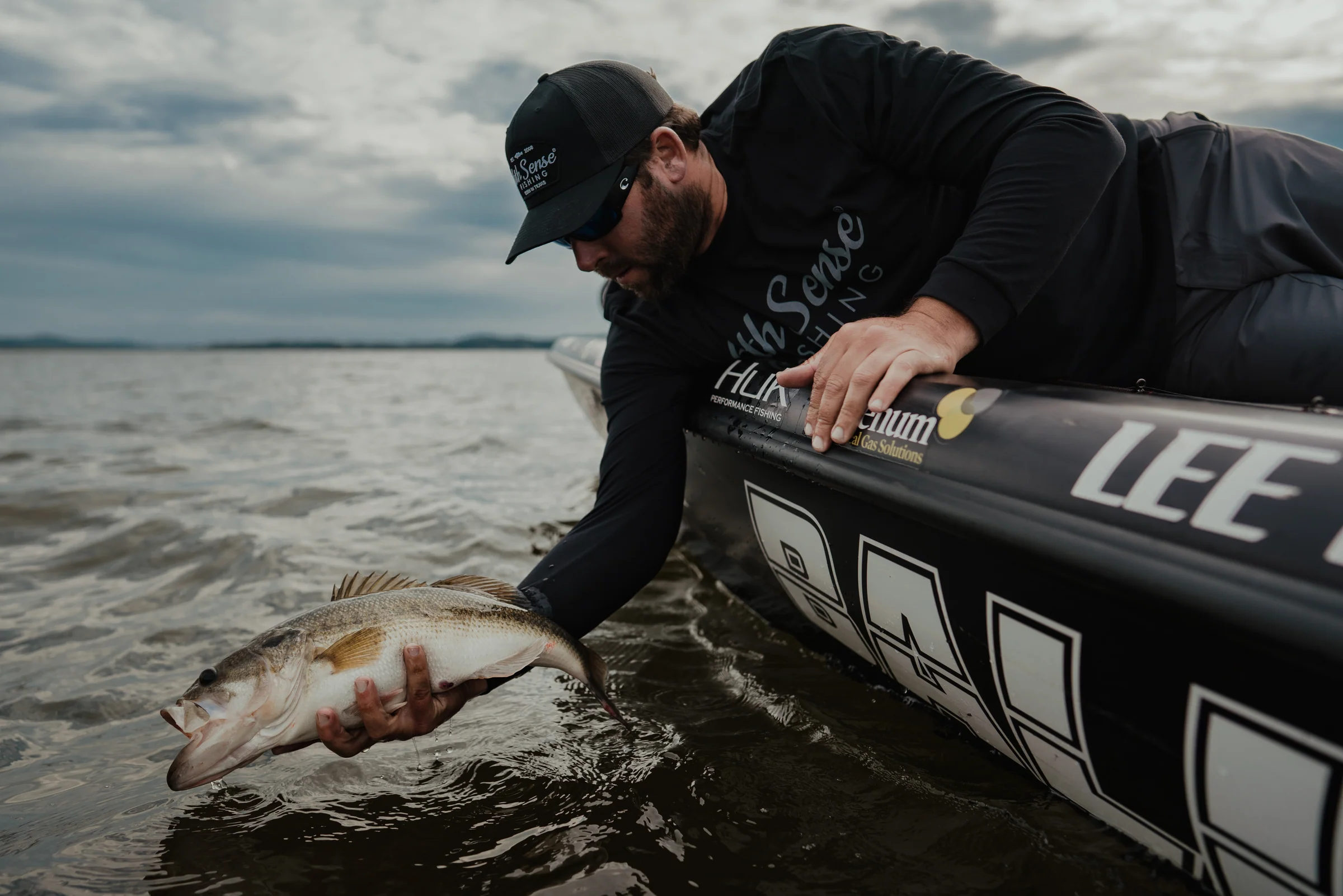 Angler leaning from a boat to release a fish at the waterline