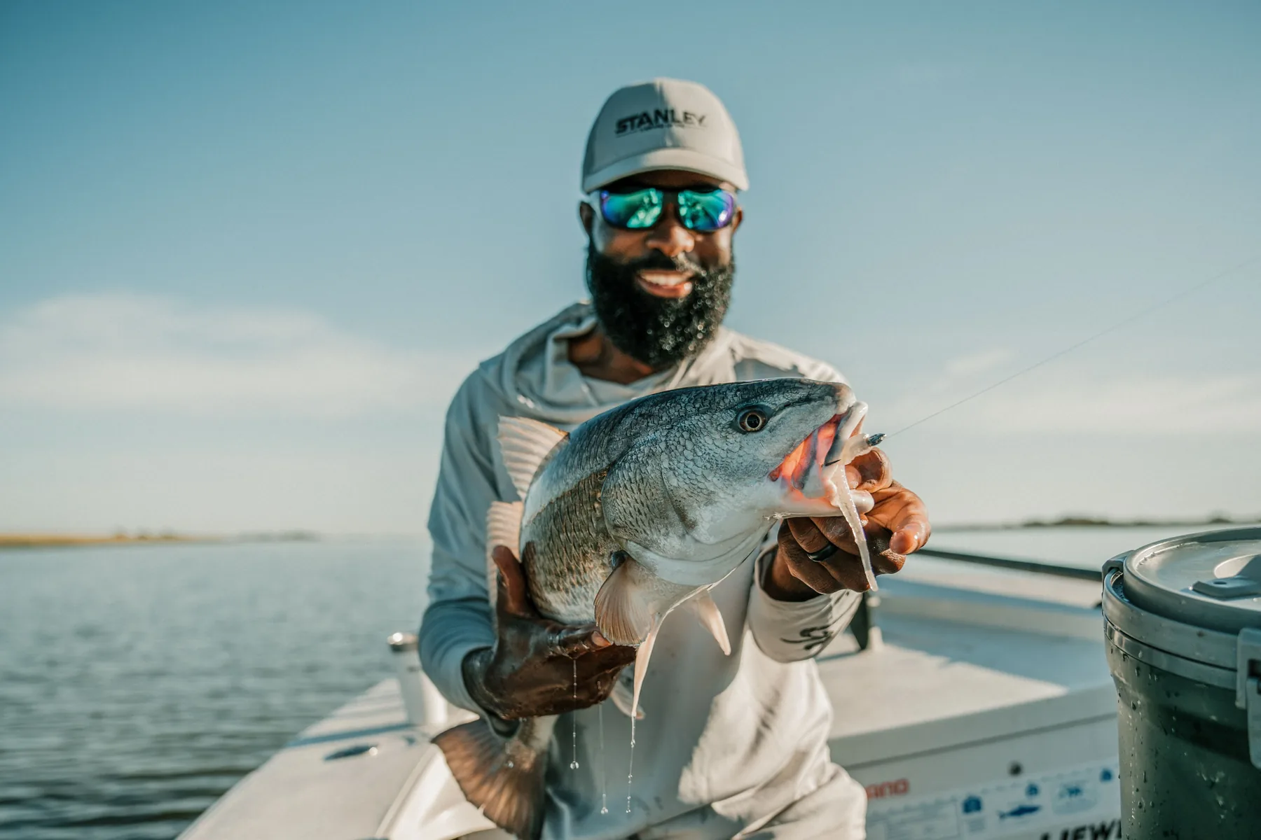Angler holding a fish on a boat during an outdoor brand shoot